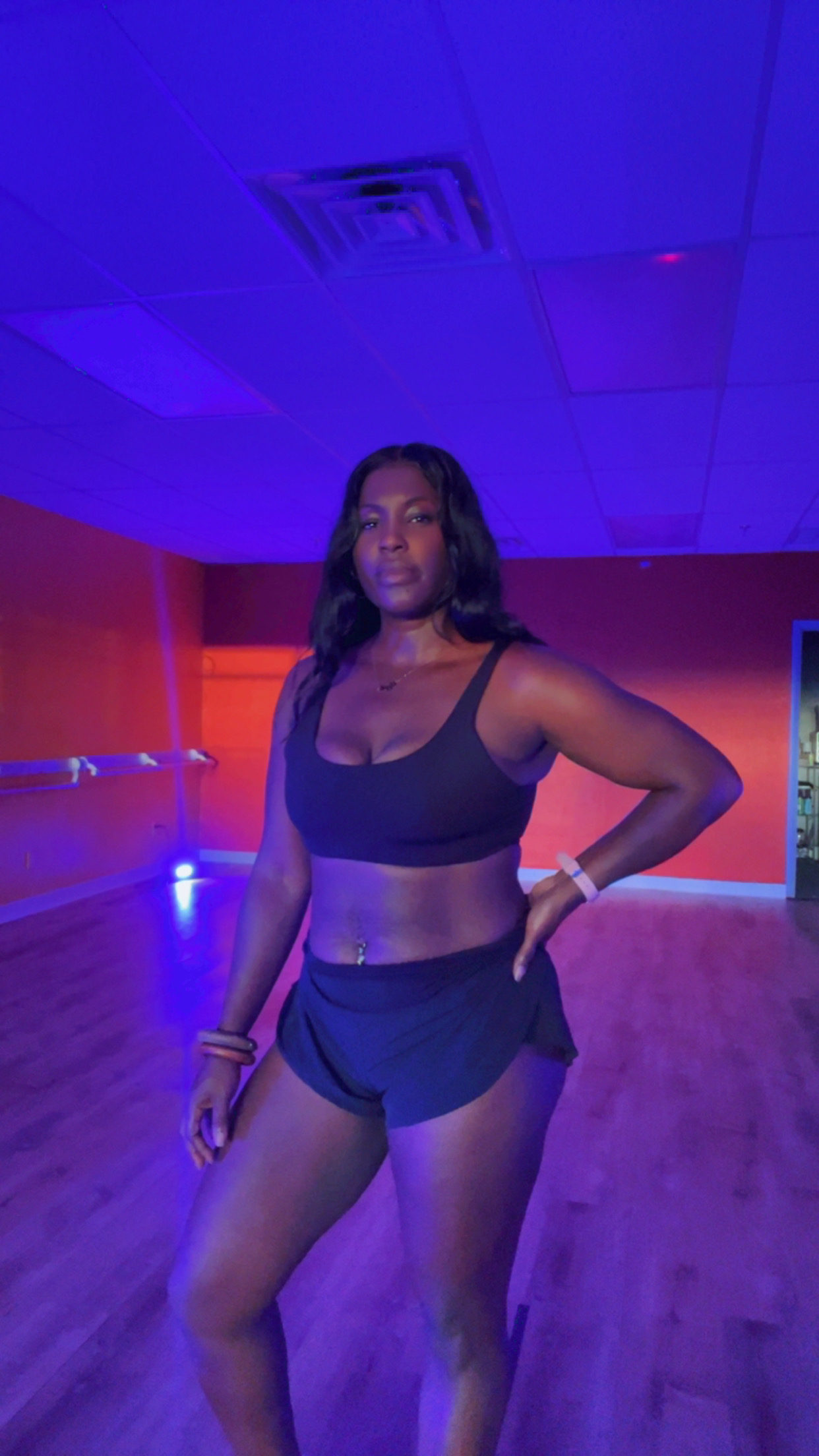 Melisa mid-move in a studio washed in purple and red light