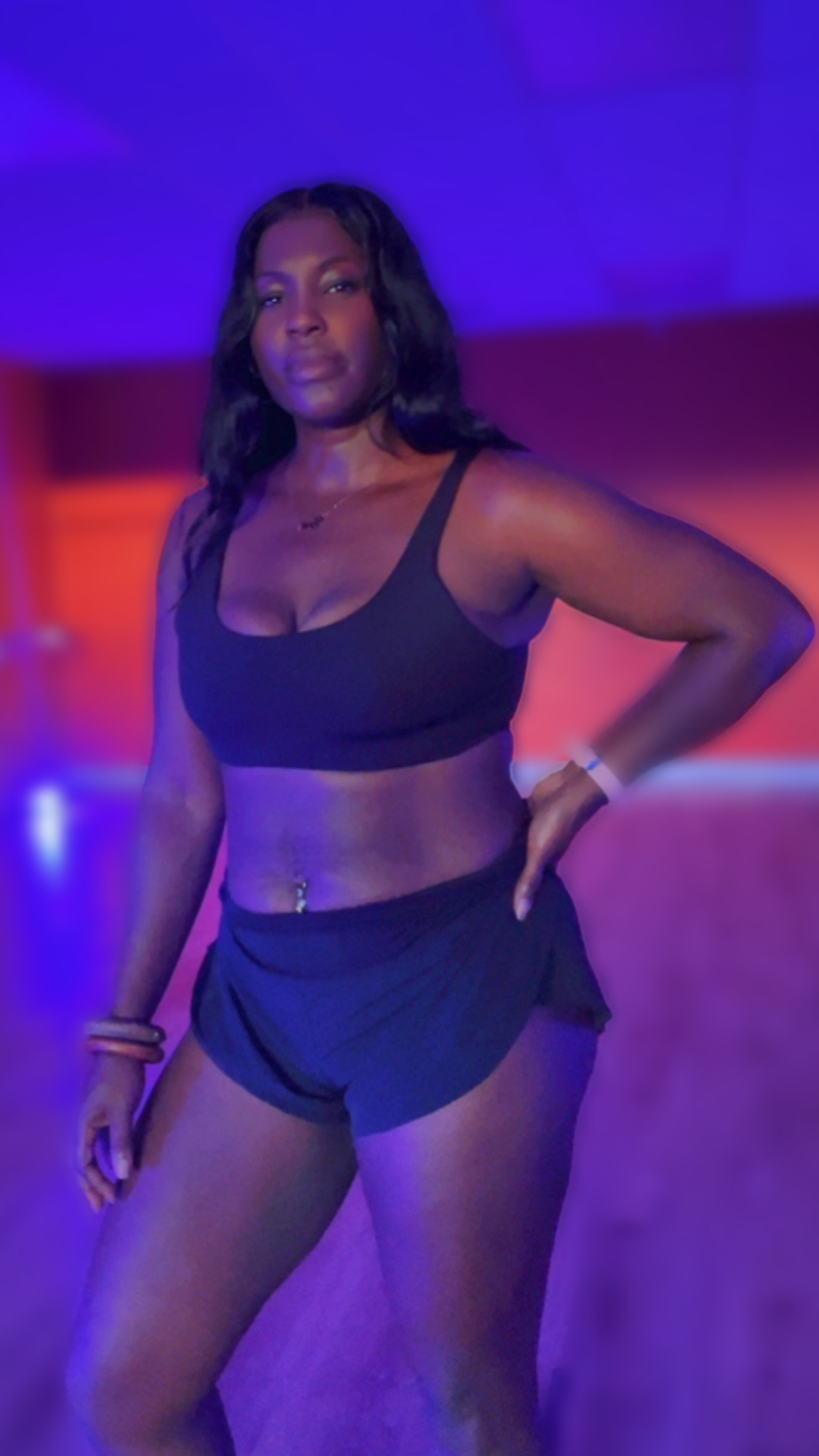 Melisa standing confident in a purple-lit studio