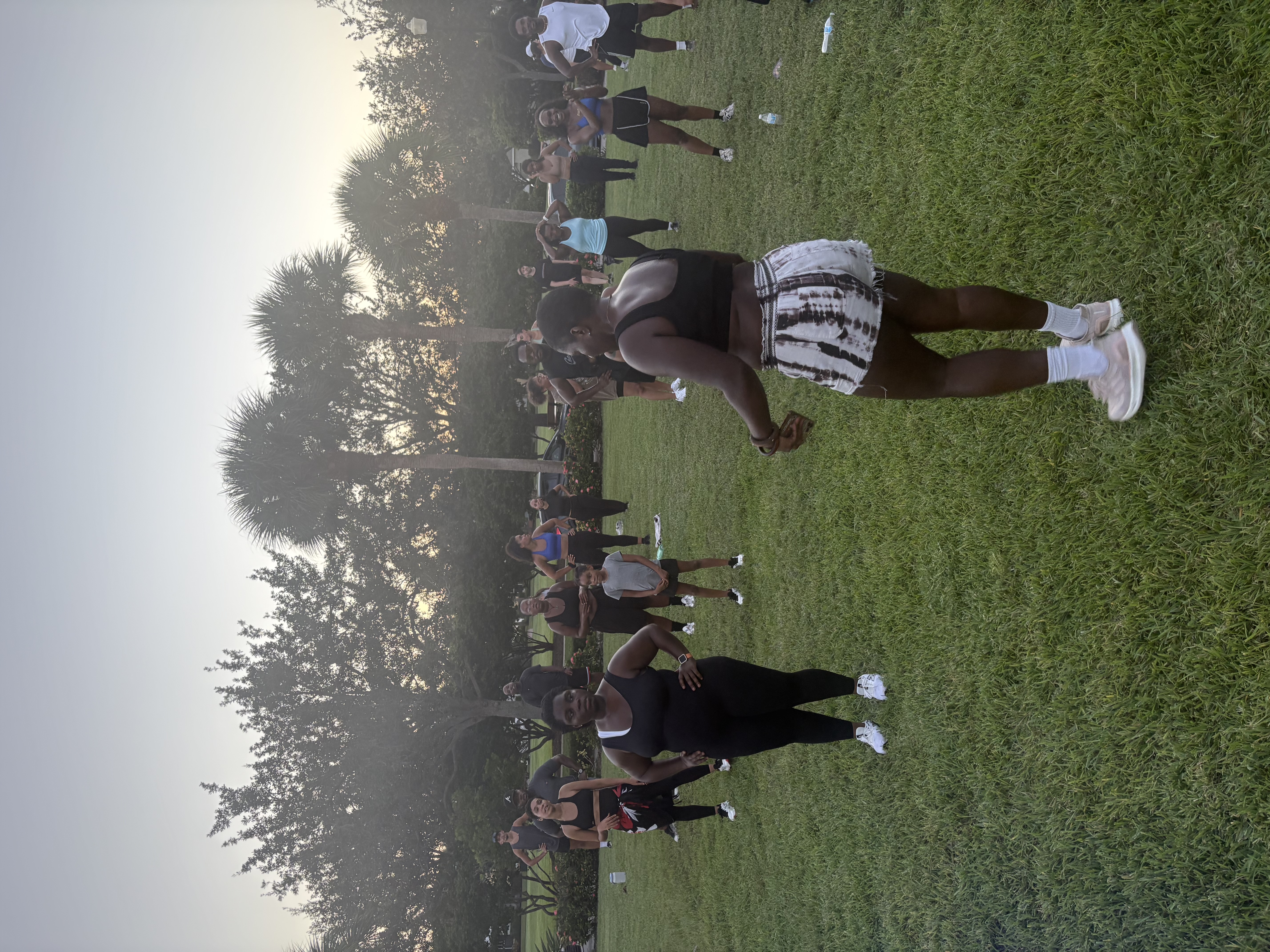 A group fitness class stretching on the grass at a Port Saint Lucie park at sunset